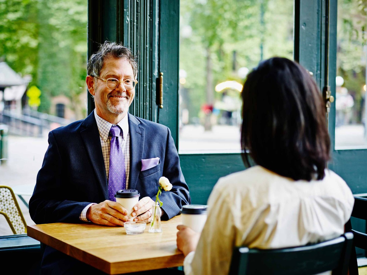 A woman meeting with an advisor with coffee in hand